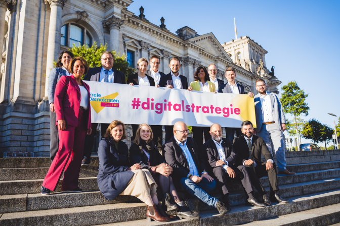 Abgeordnete halten vor dem Reichstag Banner #digitalstrategie hoch